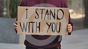 I STAND WITH YOU on cardboard poster in hands of male protester activist. Stop Racism concept, No Racism. Rallies