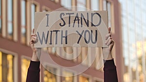 I STAND WITH YOU on cardboard poster in hands of male protester activist. Stop Racism concept, No Racism. Rallies