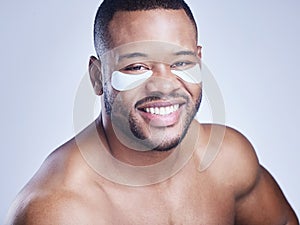 I stepped up my beauty game. Studio shot of a handsome young man wearing an under eye patch against a blue background.