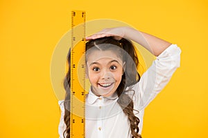 I am still growing. Tall kid. Kid school uniform hold ruler. Pupil cute girl with big ruler. Geometry school subject