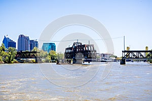 The I Street Bridge is a historic metal truss swing bridge located on I Street in Sacramento; the city's downtown skyline in the