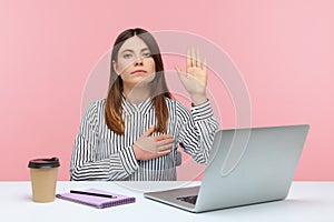 I swear! Honest dedicated woman office worker raising hand to give promise sitting at workplace, taking oath with trustworthy