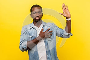 I swear! Portrait of honest serious man keeping hand on chest and raising palm. indoor studio shot isolated on yellow background