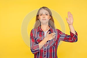 I swear, promise! Portrait of sincere honest ginger girl in shirt holding hand up and on chest, pledging allegiance, taking oath