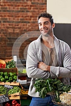 I always take the healthy choice. Portrait of a young man in a grocery store holding a basket full of fresh produce.