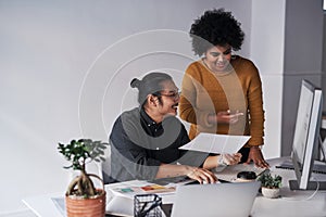 I think you should do this. two young businesspeople working together with a computer and paperwork in the office.