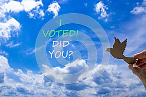 I voted. Did you symbol. Concept words I voted. Did you. Beautiful blue sky cloud background. Voter hand with wooden bird.