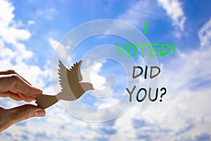 I voted. Did you symbol. Concept words I voted. Did you. Beautiful blue sky cloud background. Voter hand with wooden bird.