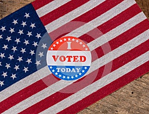 I Voted Today paper sticker on US Flag and rural wooden table