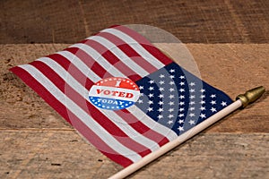 I Voted Today paper sticker on US Flag and rural wooden table