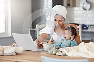 I was hoping youd have some ideas for me. a woman eating rusks while working on her laptop and holding her baby on her