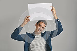 I was just thinking out loud about this. Studio portrait of a young man holding a blank placard against a grey