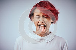 I was not made to be subtle. Studio shot of an attractive young woman screaming against a gray background.