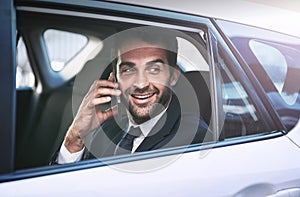 I am on the way. a handsome young businessman making a phonecall while being driven to work.