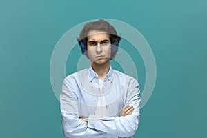 I will not do it. Portrait of a young beautiful man wearing white t-shirt and blue shirt with headphones fold ones arms and