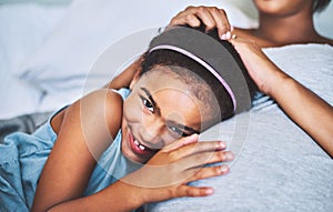 I wont be the youngest anymore. Portrait of a cheerful little girl relaxing on the bed with her pregnant mother at home