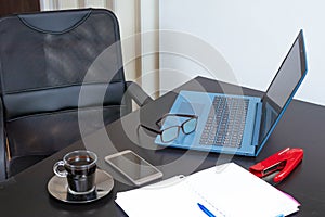 I work from home. Home table with a laptop, a notebook, glasses, coffee and cell phone. Side view