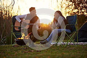 I wrote this for you. Shot of a young man serenading his girl while playing guitar during a camping trip.