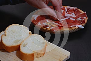 Iberian or Serrano ham on a wooden plate, accompanied with bread. Typical Spanish dish