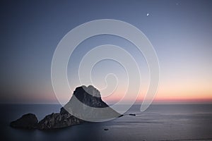 Ibizan sunset at sea with crescent moon in the dark blue sky