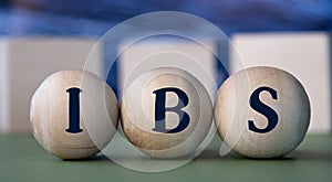 IBS - acronym on wooden balls on the background of wooden large cubes