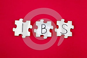 IBS Irritable Bowel Syndrome Acronym Written on Wooden Puzzles on a Red Background