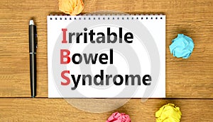 IBS irritable bowel syndrome symbol. Concept words IBS irritable bowel syndrome on white note on a beautiful wooden background.
