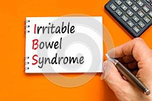 IBS irritable bowel syndrome symbol. Concept words IBS irritable bowel syndrome on white note on a orange background.