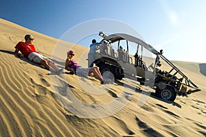 ICA, PERU - JULY 6, 2010: Sand dune buggy parked on a dune and group of people having fun. Ica, Peru