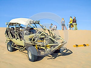 ICA, PERU - JULY 6, 2010: Sand dune buggy parked on a dune and group of people having fun. Ica, Peru