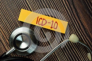 ICD - 10 write on sticky note and stethoscope isolated on Wooden Table. Medical Concept photo