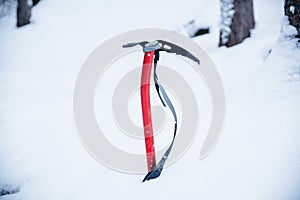 The ice ax is needed for climbing. Close-up of an ice ax in the snow.