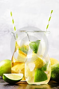 Ice black and green tea with lemon, lime and ice in the jug, selective focus