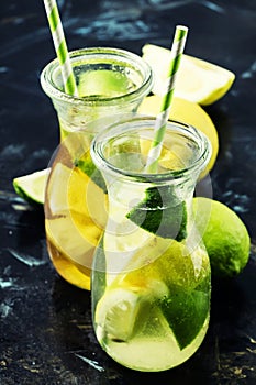 Ice black and green tea with lemon, lime and ice in the jug, selective focus