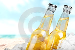 Beer bottles in ice on beach background