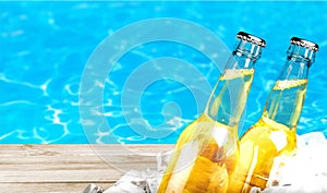 Beer bottles in ice on pool background