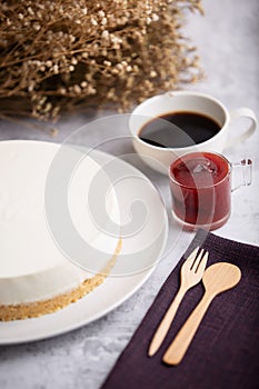 Ice box cheese cake with strawberry jam and a cup of coffee on the table