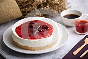 Ice box cheese cake with strawberry jam and a cup of coffee on the table