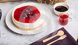 Ice box cheese cake with strawberry jam and a cup of coffee on the table