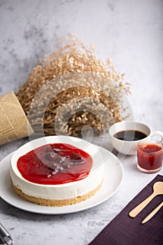 Ice box cheese cake with strawberry jam and a cup of coffee on the table