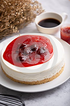 Ice box cheese cake with strawberry jam and a cup of coffee on the table