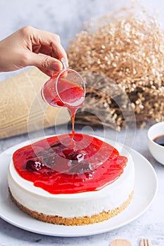 Ice box cheese cake with strawberry jam and a cup of coffee on the table