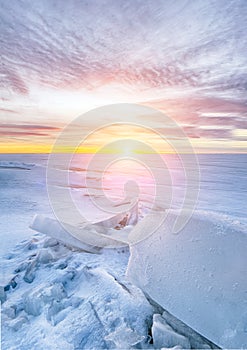 Ice braking on frozen lake, sunset in winter.