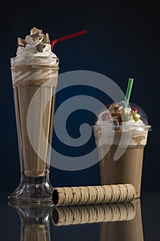 Ice caffe in glass and plastic takeaway cup, decorated with whip