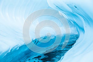 Ice canyon through a glacier in remote Alaska. Melting glacier river cuts through the surface creating overhanging ice