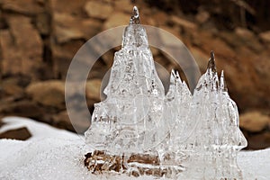 Ice castles against a background of brown rocks.