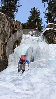 Ice climber free solo climbing an ice fall in the Swiss Alps