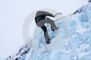 Ice climber scaling ice wall