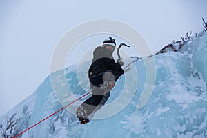 Ice climber scaling ice wall