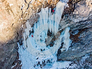 Iceclimber climbing steep frozen icefall. Extreme winter sports photo